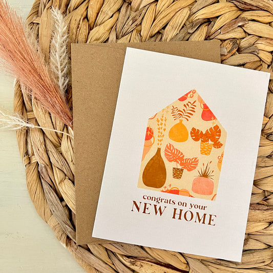 Greeting card with house illustration and 'Congrats on your New Home' text on a woven mat.