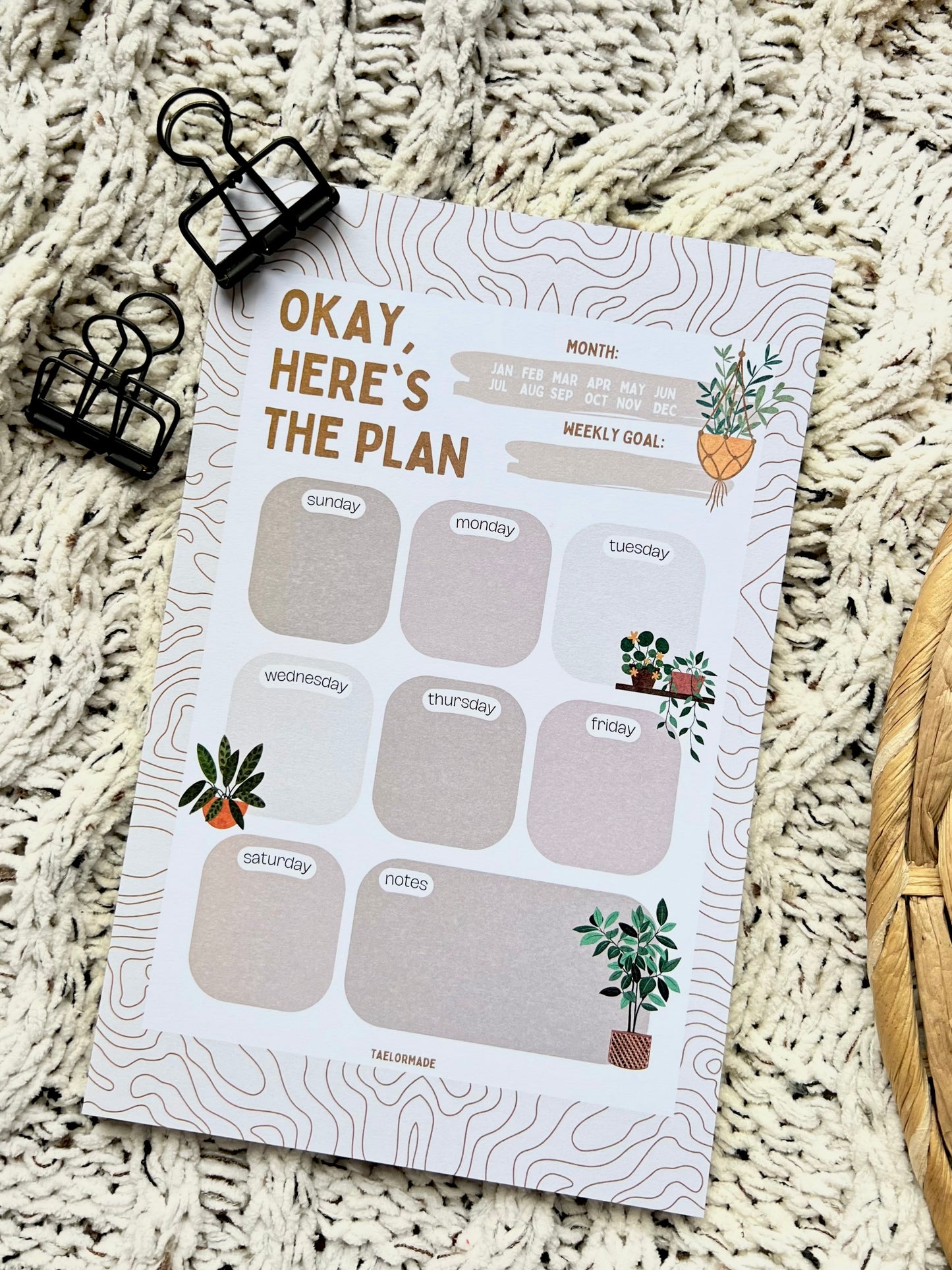 Weekly planner notepad with plant-themed design on a textured surface