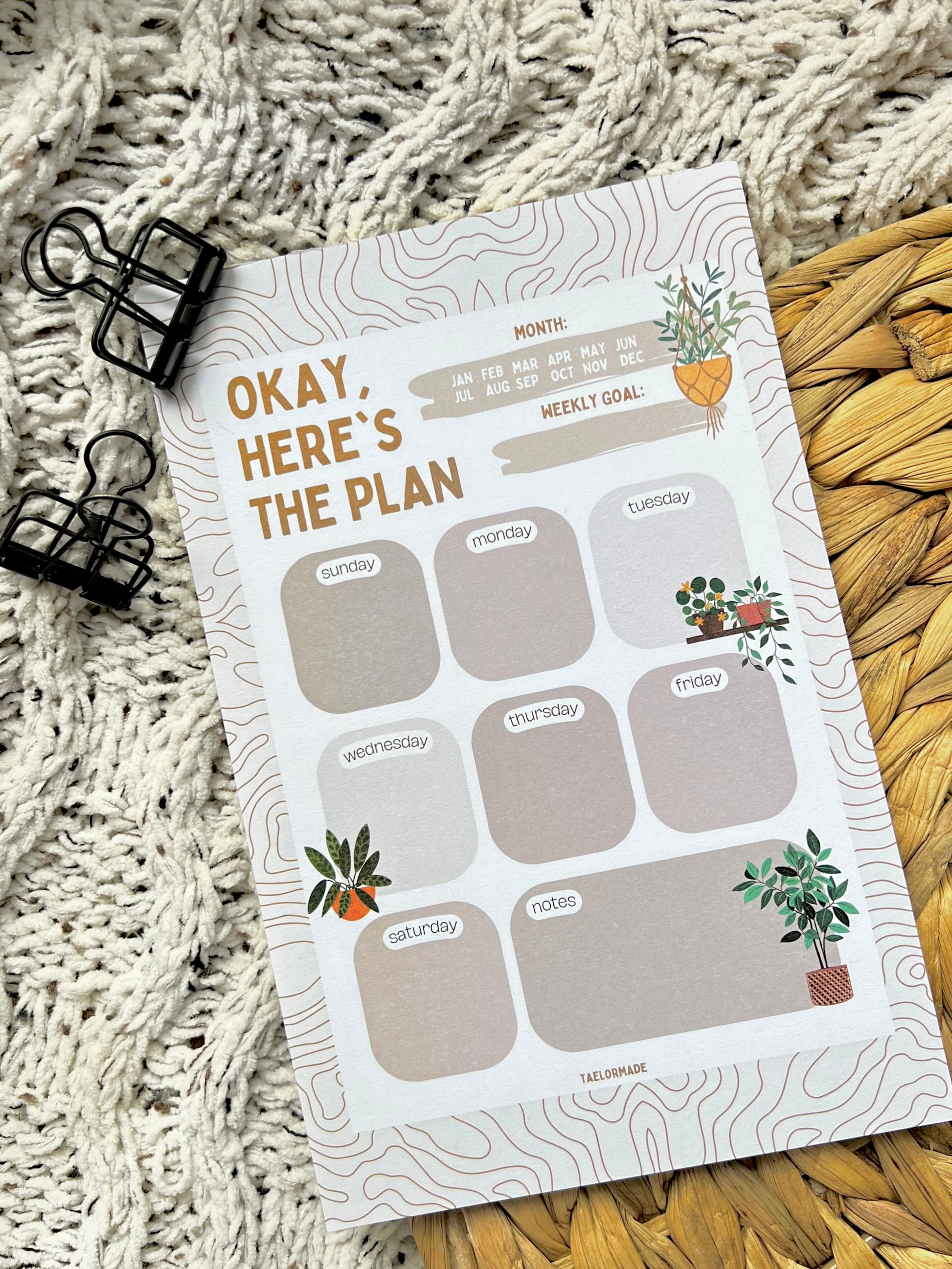 Weekly planner notepad with plant illustrations on a textured surface