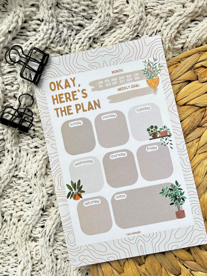 Weekly planner notepad with plant illustrations on a textured surface
