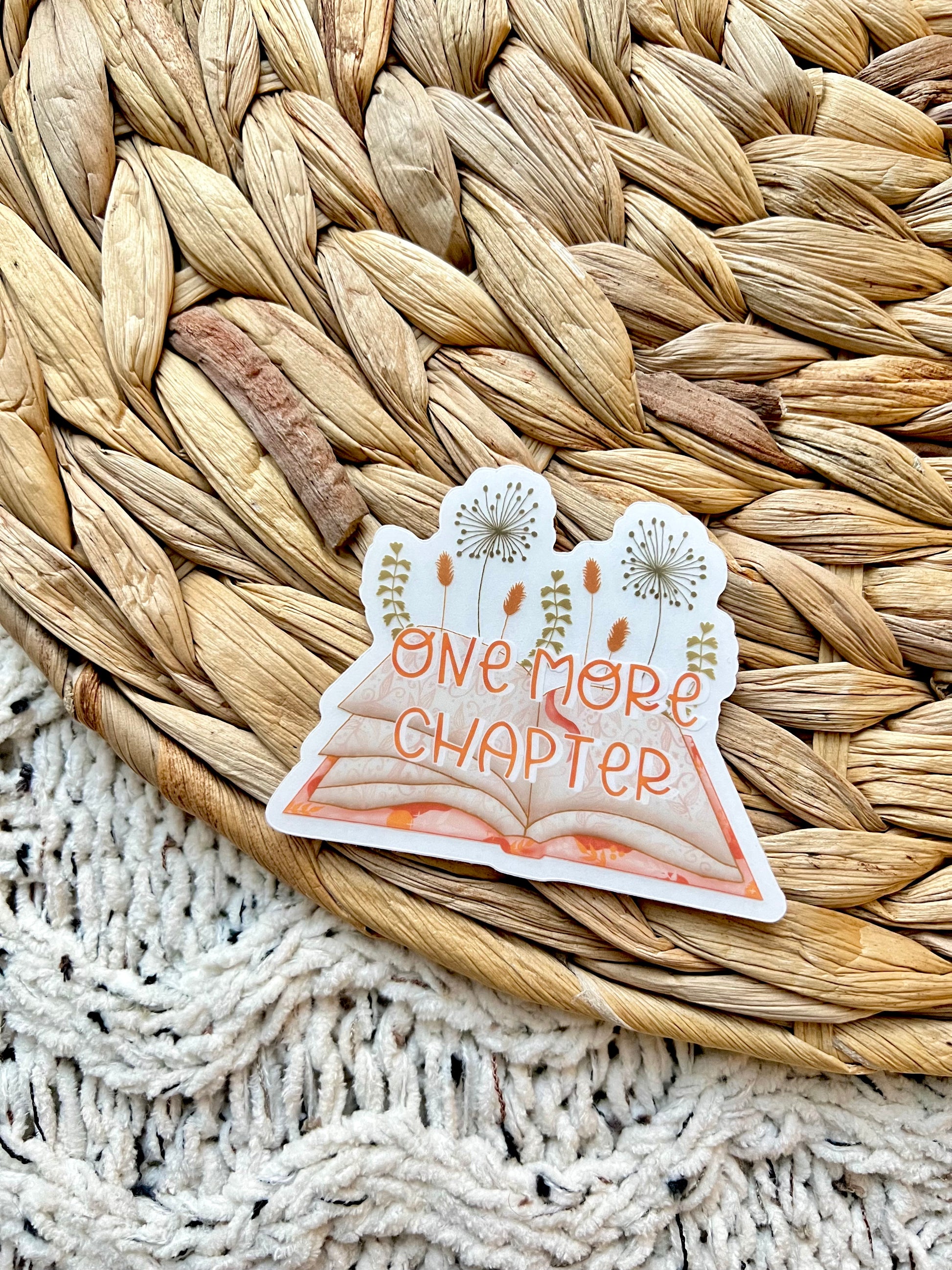 Sticker with 'One More Chapter' text on a woven mat