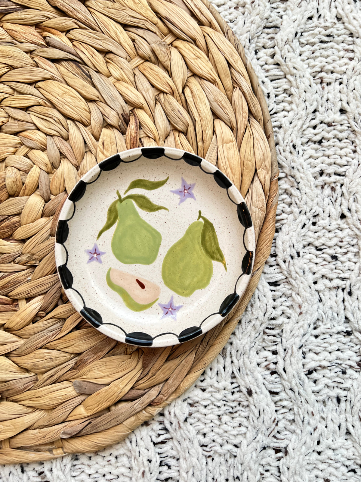 Decorative ceramic dish with pear design on a woven mat