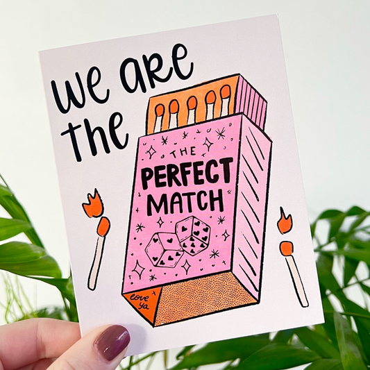 Illustration of a matchbox with 'We are the perfect match' text on a card, held against a green leafy background.