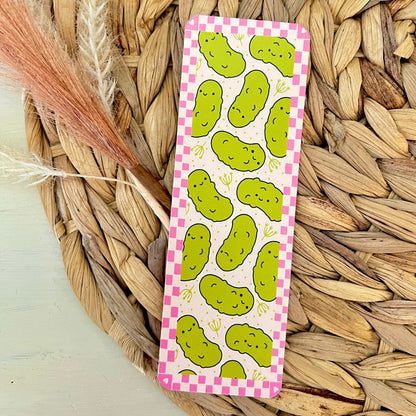 Bookmark with green pickle pattern on a pink checkered background, placed on a woven mat.