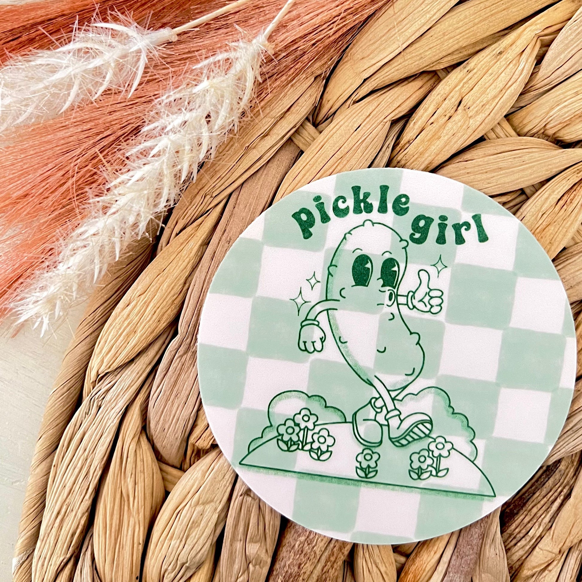 Sticker with 'Pickle girl' design on a checkered background, placed on a woven surface.