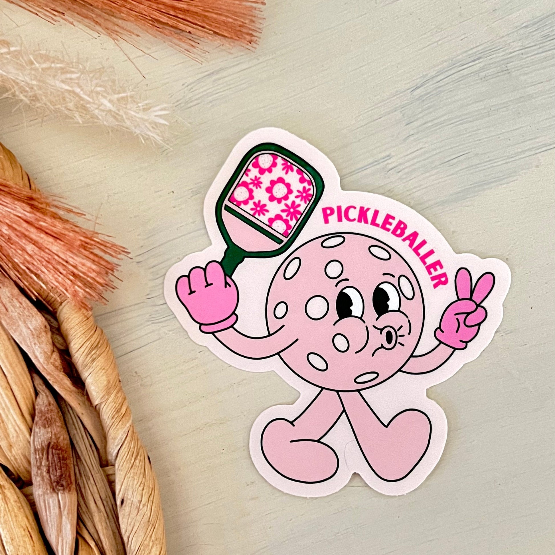 Pink pickleball-themed sticker with cartoon character on a light background
