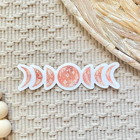 Set of pink moon phase stickers on a textured woven surface with wooden beads.