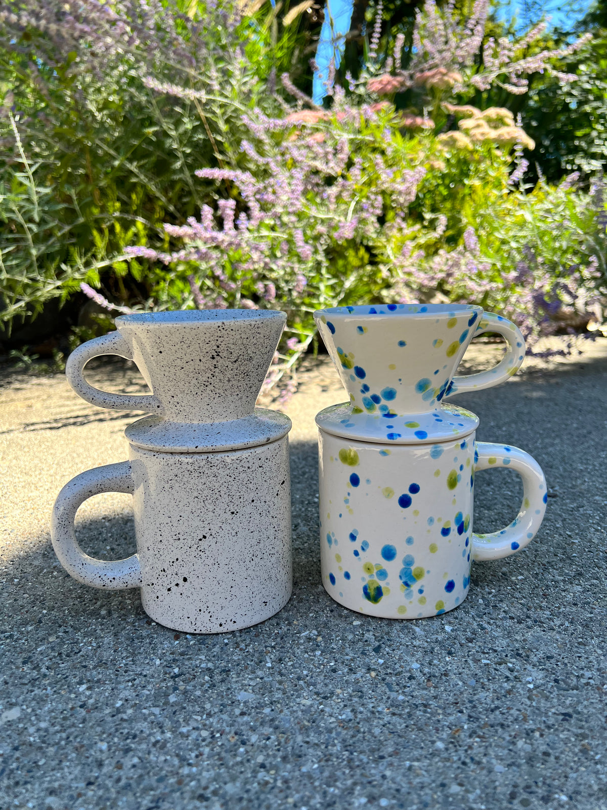 Set of ceramic mugs with speckled and polka dot patterns outdoors.