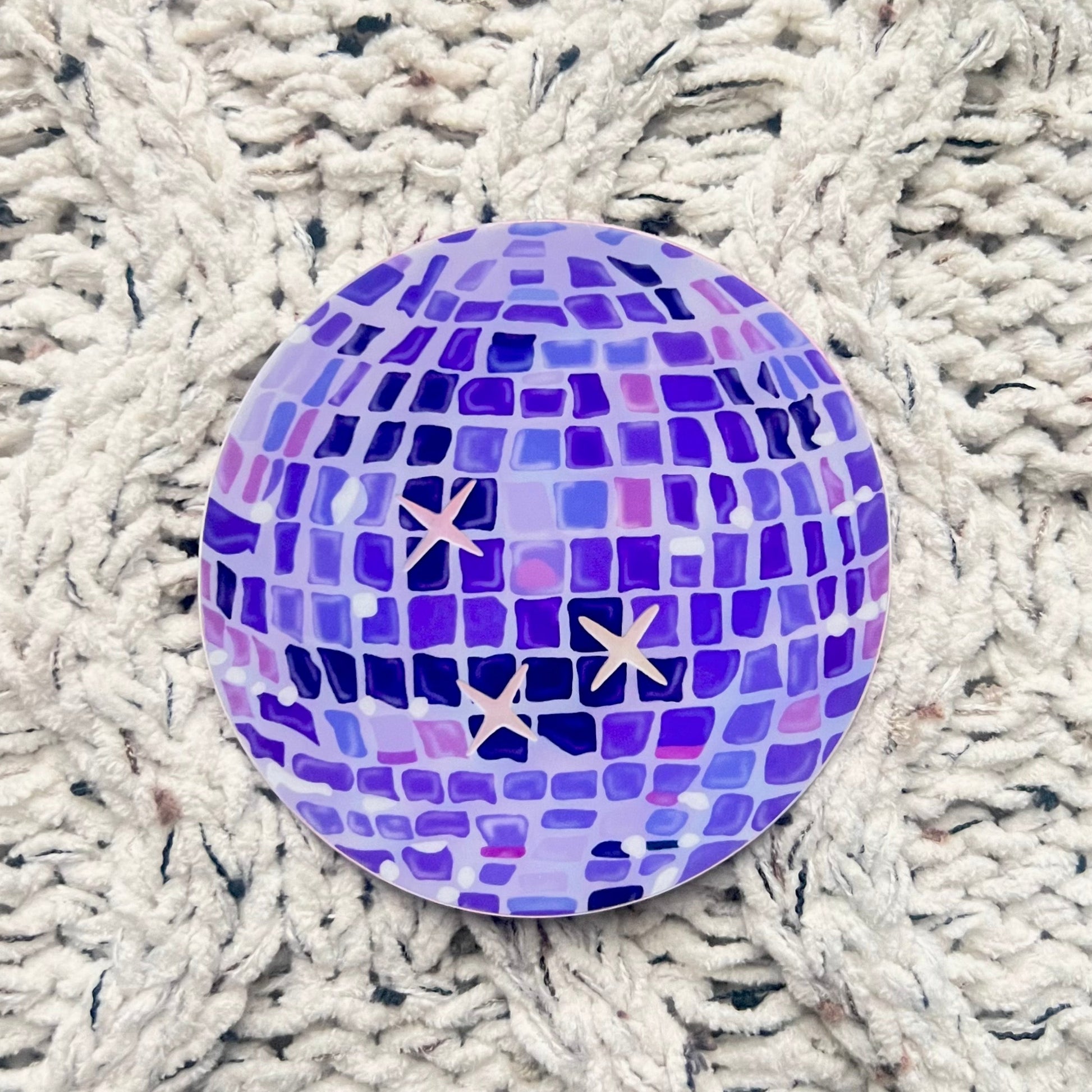 Purple disco ball illustration sticker with holographic stars on a woven blanket