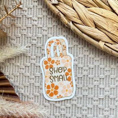 Sticker with 'Shop Small' text on a textured surface