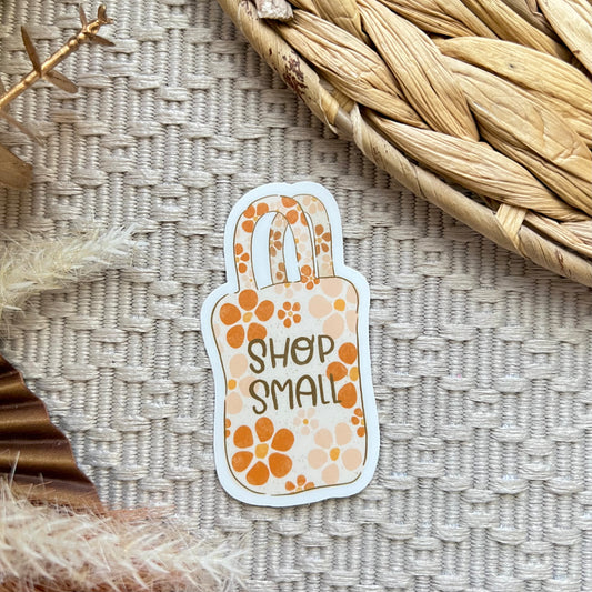Sticker with 'Shop Small' text on a textured surface