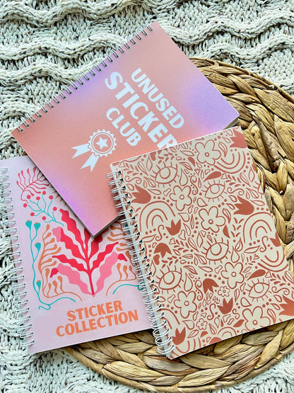 Three spiral-bound notebooks with floral patterns on a textured surface