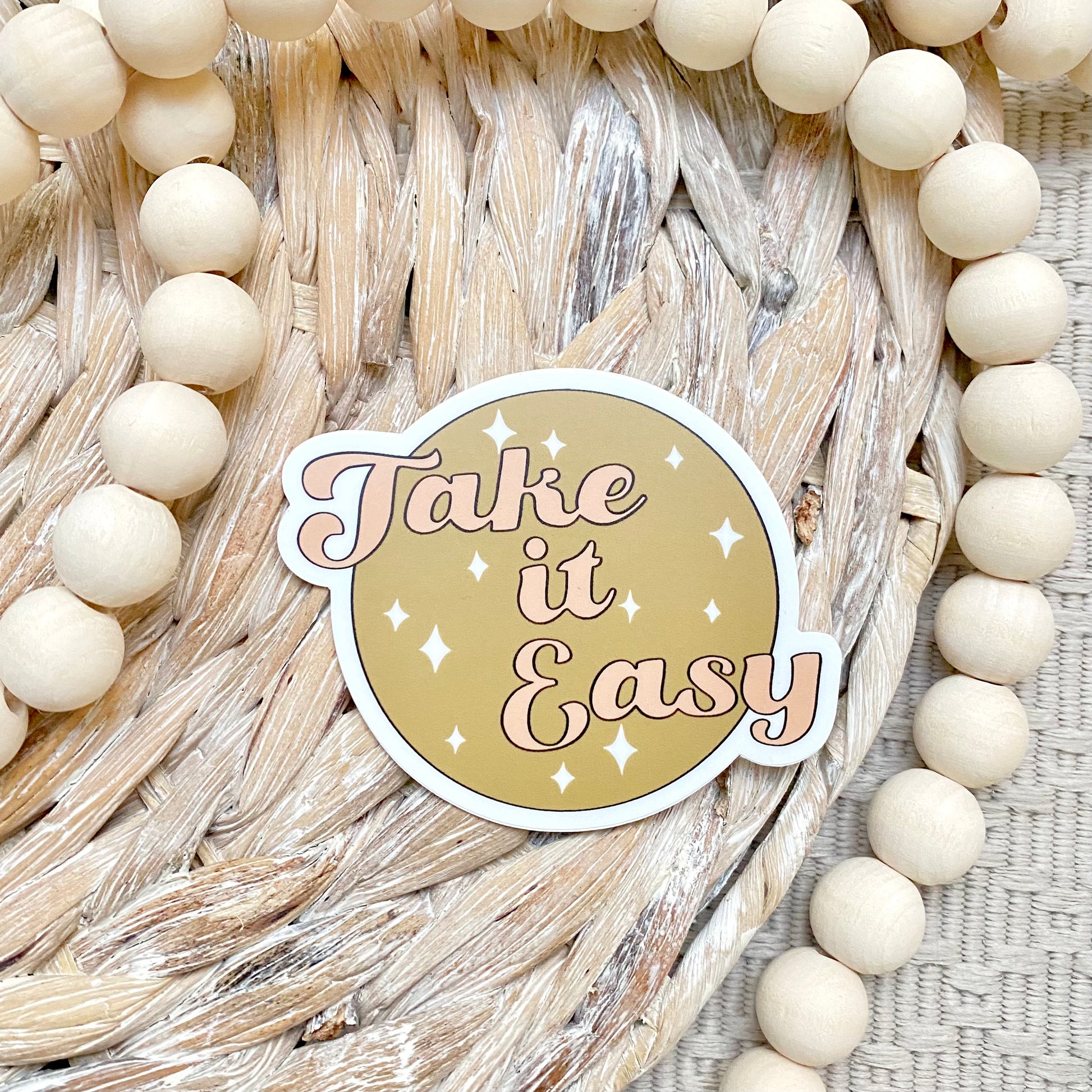 Sticker with 'Take it Easy' text on a woven background with beads