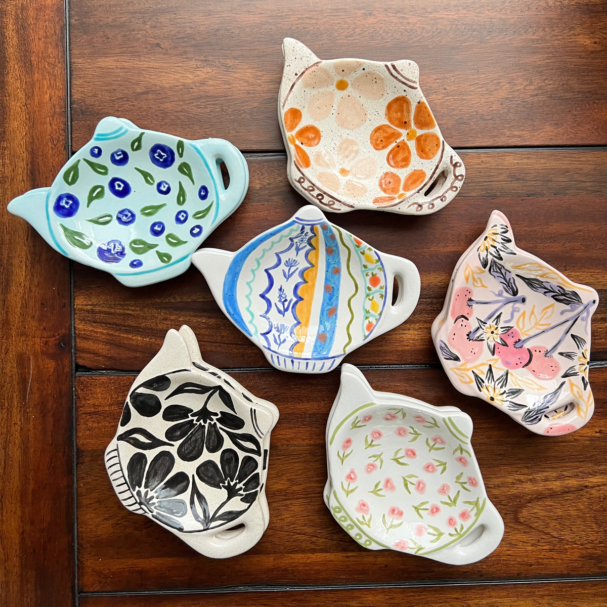 Set of six ceramic dishes with floral patterns on a wooden surface