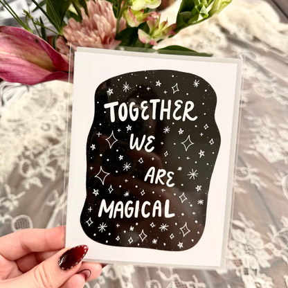 Card with 'Together We Are Magical' text held by a hand with flowers in the background