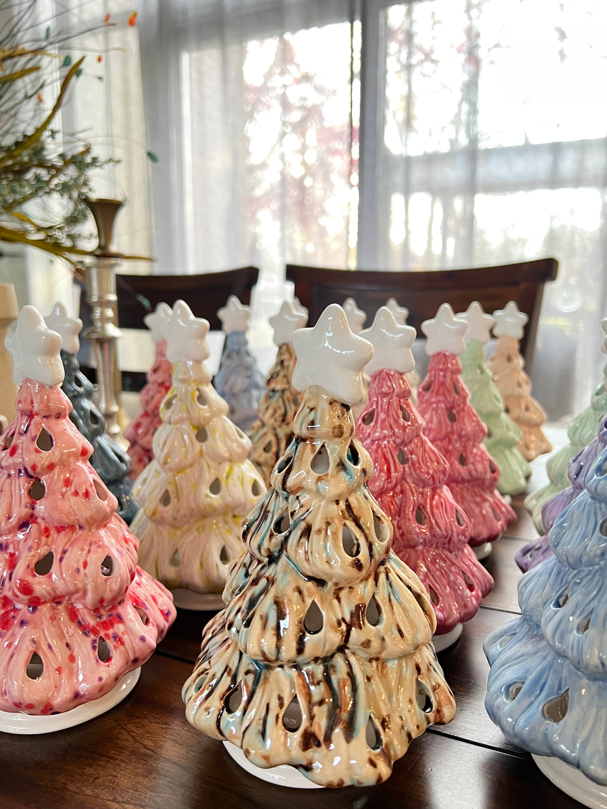 Decorative ceramic Christmas trees in various pastel colors on a table.