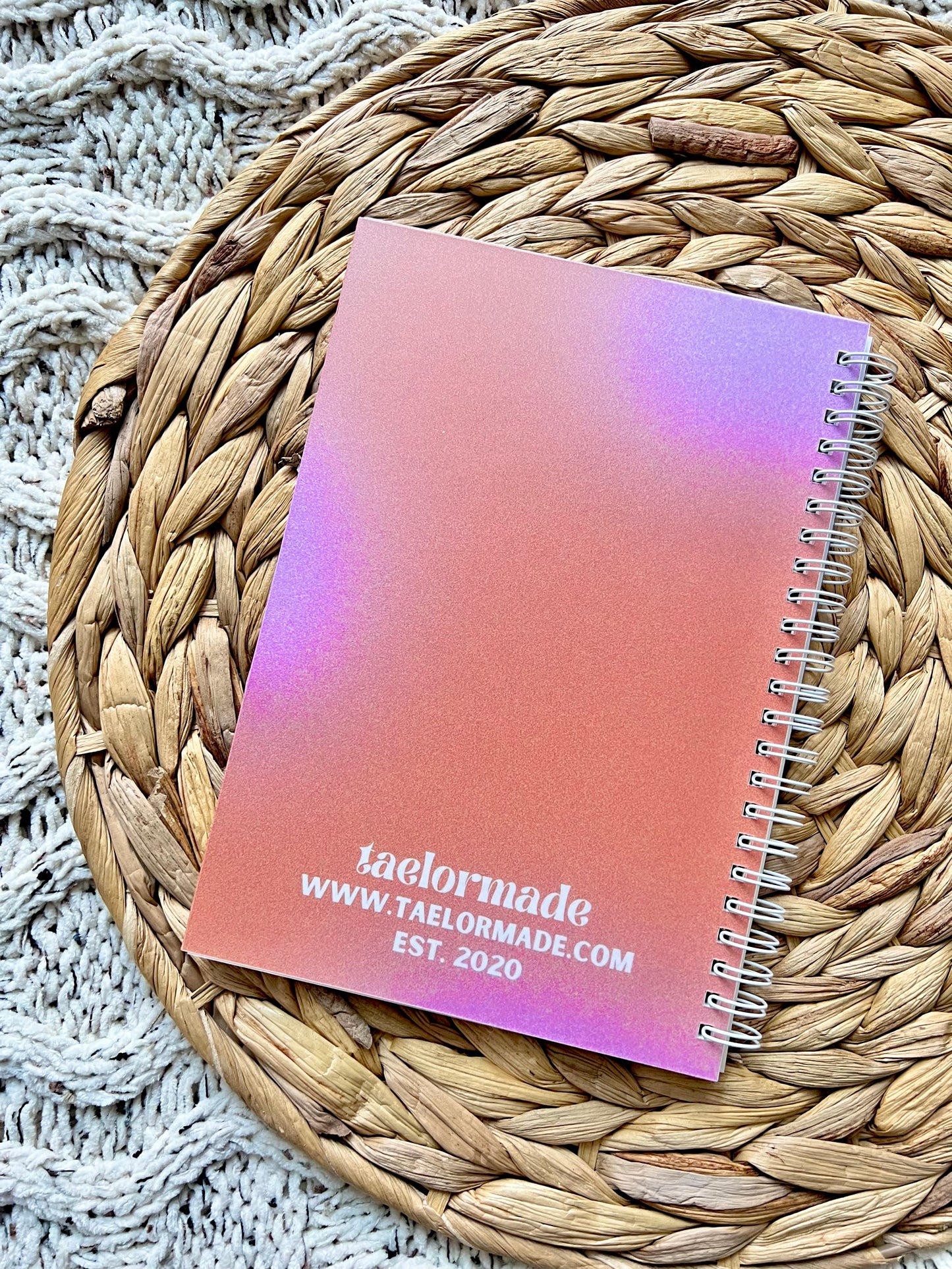 Spiral-bound notebook with gradient cover on a woven mat